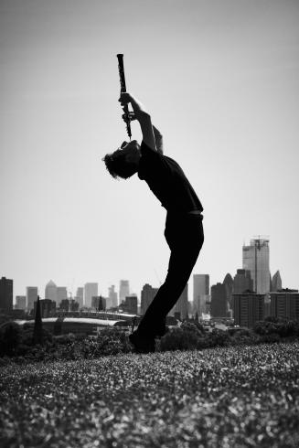 Man with oboe in front of city skyline 